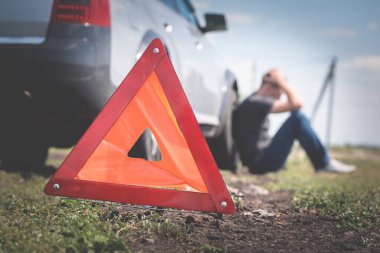 Sürücü ön planda uyarı üçgeniyle el ele tutuşuyor. Bozuk araba.. 