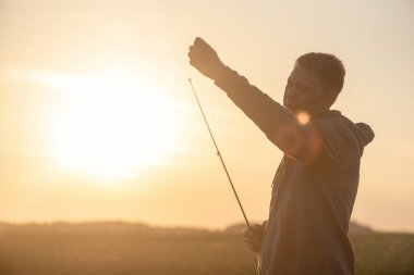 Balıkçı elinde olta ile dışarıda.