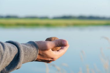 Balıkçı elinde bir balık tutuyor. Topla besleniyor..