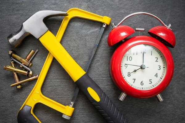 Red alarm clock and work tools on the table. Repair time abstract background.