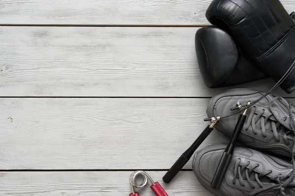 Boxing gloves, sport shoes and jumping rope on a wooden flat lay background with copy space.
