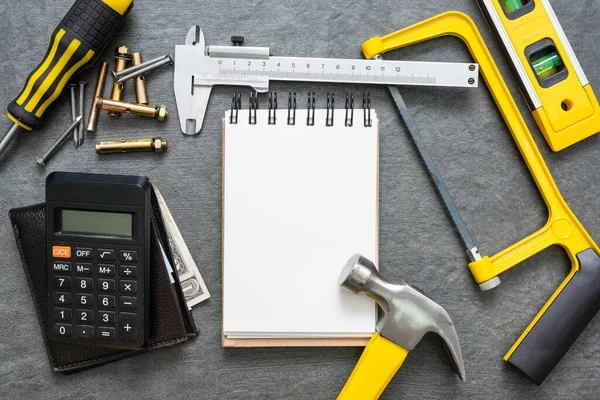 Construction cost or repair calculation mockup. Blank page notepad and work tools on the workbench.