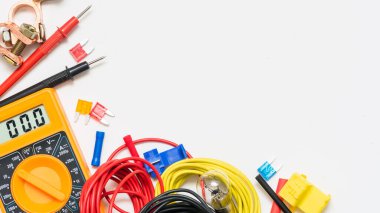 Beyaz arka planda fotokopi alanı olan elektrikli araba aksesuarı. Çoklu metre, araba aküsü terminalleri, kablolar ve sigortalar..