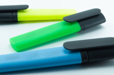 Beyaz arka planda izole işaretler var. Mavi, yeşil ve sarı fosforlu kalemler hizada..