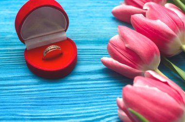 Lale çiçekleri ve alyans hediye kutusunda mavi ahşap masa zemininde. Evlilik teklifi. Sevgililer Günü romantik arkaplanı. Teklif..