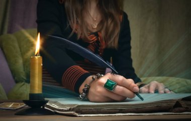 Falcı masasında tarot kartları. Gelecek okumaları. Kadın cadı tüy kalemle sihirli bir parşömen kitabı yazıyor. Yazar.