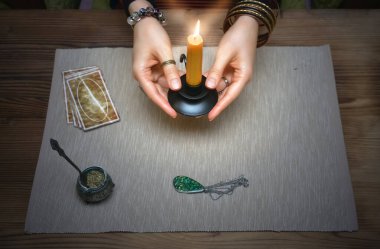Falcı masasında tarot kartları. Gelecek okumaları. Kadın cadı elinde yanan bir mum tutuyor..
