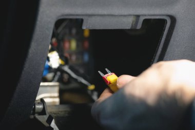 Otomobil elektrikçisinin elinde bir sigorta var. Araba sigortası yenilemesi.