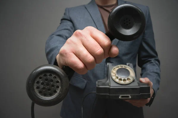 Rotary phone handset in man hand close up on gray background.