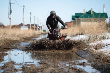 Dörtlü bisikletteki motosiklet kirli yolda gidiyor..