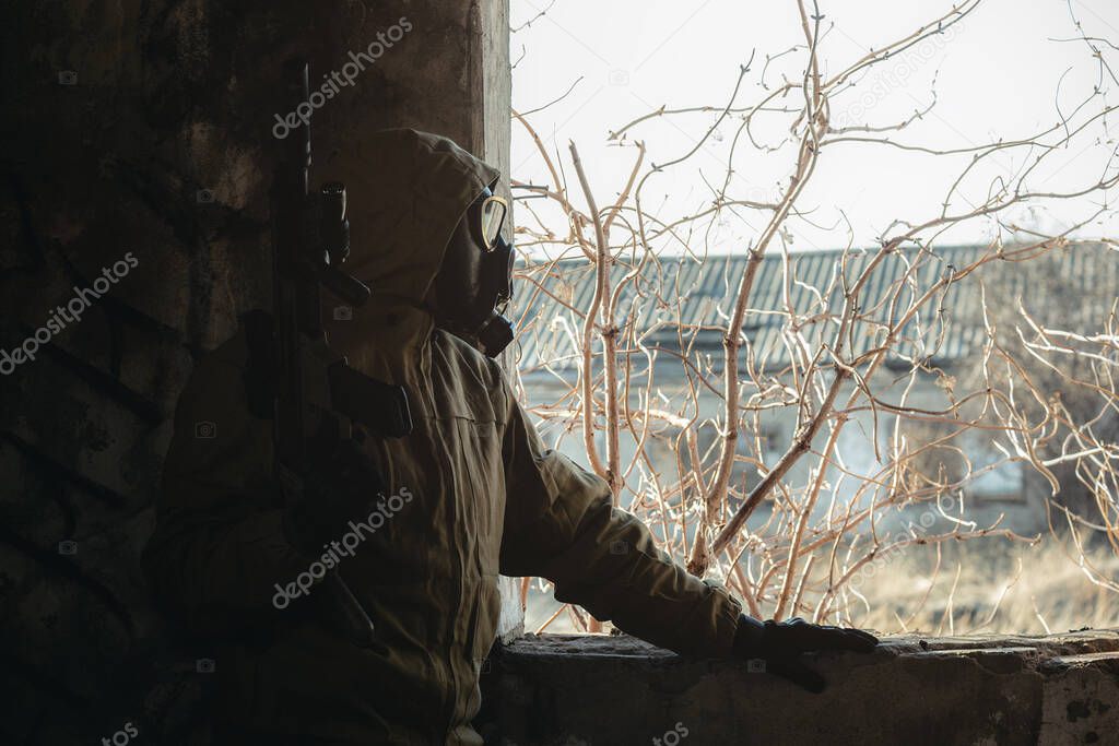 Soldier in gas mask and with rifle in the abandoned building.