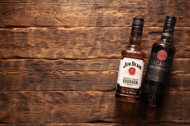 Moskova, Rusya - 30 Haziran 2019: Bacardi rom ve Jim Beam viski şişeleri ahşap masa arkasında.