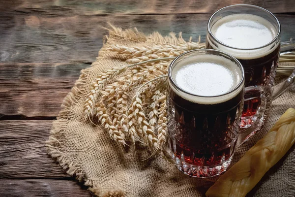 A pair mugs with a frothy beer on the table.