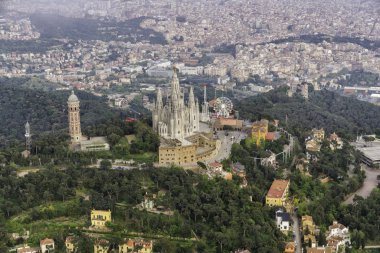 İspanya'nın Barselona şehrine bakan eğlence parkı ile Tibidabo dağının etrafında uçmak. Havadan helikopter görünümü