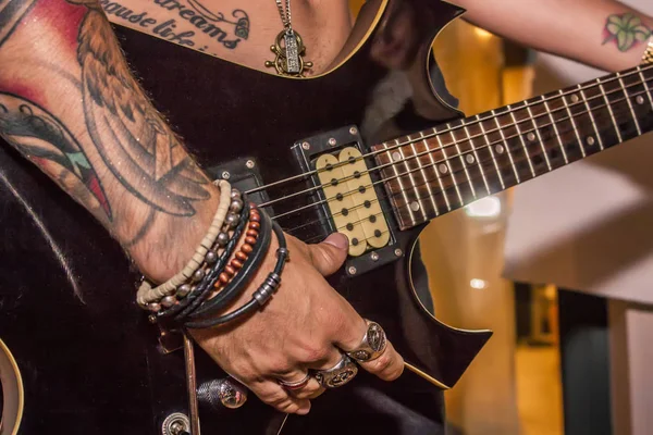 stock image Detail of a tattooed boy playing electric guitar during a rock cone.