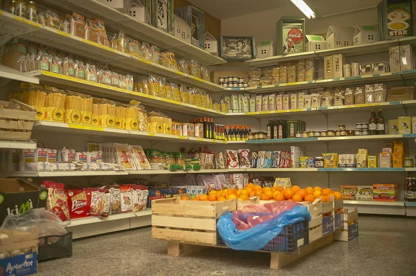 Gıda paketleri ve meyve kutuları dolu bir bakkal raflarında.