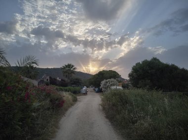 Sardunya 'nın güneşin batışıyla aydınlanan tepecikli manzarası bulutların arkasında kaybolacak..