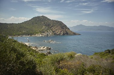 İtalya 'nın güneyindeki Sardunya' da deniz, dağlar ve Akdeniz bitkilerinin bulunduğu doğal bir körfezin panoramik manzarası, özellikle de Cala Sa Figu plajının.