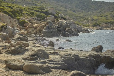Akdeniz kıyısının kayalık yüzeyi denizle ve aşağıdaki kumsalla harmanlanır..