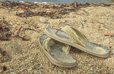 Akdeniz sahil kum üzerinde terk yıpranmış ve yıpranmış Flip-flop çifti.