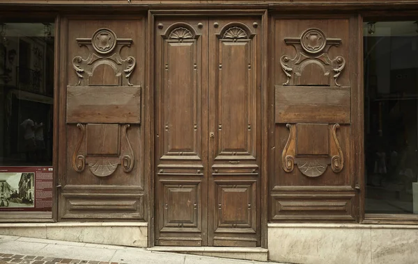 Old door of a wooden shop belonging to the historic center of Cagliari in Sardinia, Italy. Wooden door with decorations and inlays.