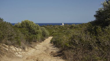Capo Ferrato Sardunyalı Panoraması Akdeniz mavi deniz horizon ile çevrili deniz feneri yol açar bir toprak yol oluşur.