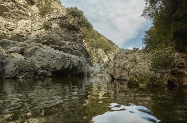 Den kayalık uçurum ile bir dağ ortasında akan bir dere ortasına görüntülemek.