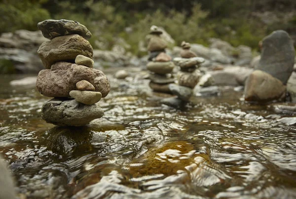 Stack of round rocks in the middle of the mountain stream water.