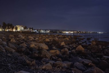 Şehrin arka plan ile gece ay ışığıyla aydınlatılan Civitavecchia kayalık plaj Panoraması deniz suya yansıyan.