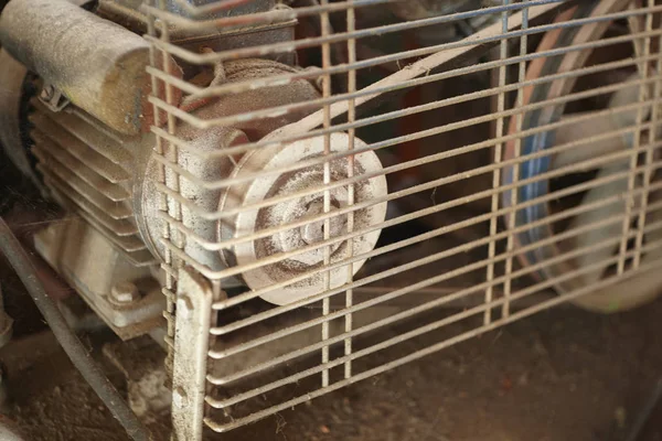 Detail of a pulley of a belt transmission protected by a grating that is part of an industrial machinery, now obsolete and worn out by the work done over the years of use.