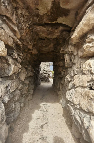 Small tunnel with stone brick walls create passages between the walls of the ruins of Tulum in Mexico