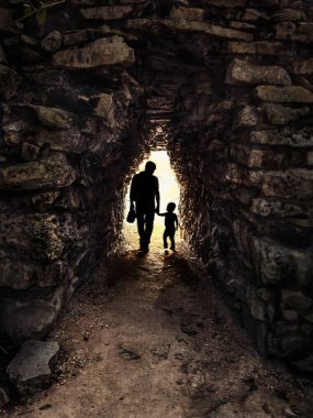 Küçük ve karanlık bir taş tünelde, arka planda baba ve oğulun silueti: Görüntü Meksika 'da Tulum' da çekildi.