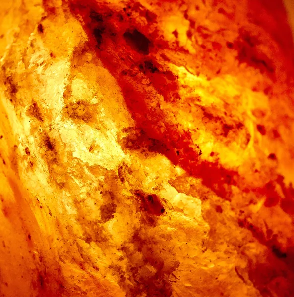 Detail of a lit salt lamp showing salt crystals illuminated by the light behind it. Square Image.