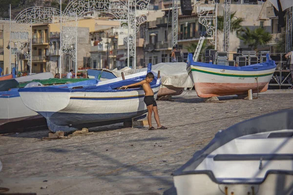 Child plays among the colorful boats — Stock Photo, Image