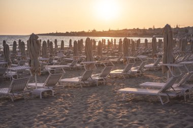 Gün batımında plajda şezlong ve şemsiyeler