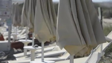 Plaj şemsiyeleri kumsalda rüzgarla kapanıyor.