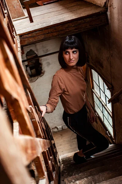 Portrait of a brunette girl in a staircase of an abandoned House, image in low light