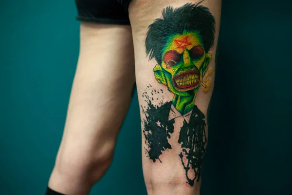 Coloured Tattoo with green face painted in a leg