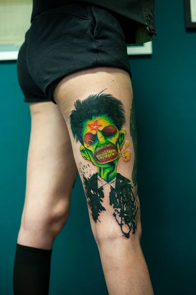 Coloured Tattoo with green face painted in a leg