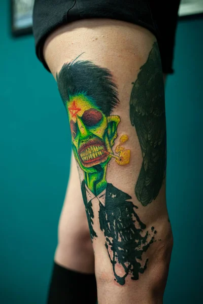 Coloured Tattoo with green face painted in a leg