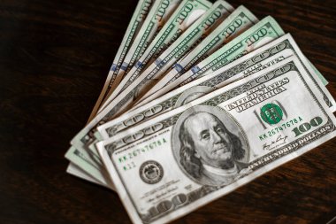 Birçok yüz dolarlık banknotlar ahşap masada dinleniyor.