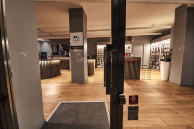 Rovigo, İtalya, 10 Eylül 2025: cam kapı hafifçe aralık, müşterileri cilalı ahşap döşemeleri, aydınlatılmış tezgahları ve cihazlarla dolu rafları olan çağdaş bir elektronik mağazasına davet ediyor