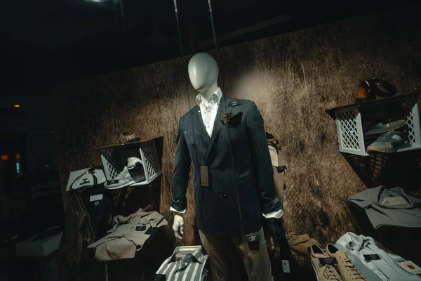 Roma, İtalya, 10 Eylül 2025. Manken şık bir çift göğüslü takım elbise, beyaz gömlek ve kravat vitrininde şık kıyafetler ve aksesuarlarla çevrili.