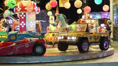 Roma, İtalya, 10 Eylül 2025: Bir tren, bir cip, bir çekici ve bir korsan gemisi de dahil olmak üzere renkli lunapark gezileri, festival ışıkları altında ışıl ışıl parlıyor, bir baba ve oğlunun dikkatini çekiyor.