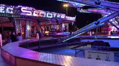 Roma, İtalya 10 Eylül 2025: renkli aydınlatılmış atlıkarınca geceleri dönüyor, yanıp sönen ışıklar ve hareket eden arabalarla canlı ve dinamik bir sahne yaratıyor.