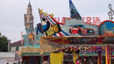 Roma, İtalya, 10 Eylül 2025: İnsanlar kırmızı bir yarış arabası, bir kale ve büyük bir trible anahtarla süslenmiş renkli bir lunapark yolculuğunun keyfini çıkarıyorlar, canlı ve dinamik bir atmosfer yaratıyorlar.