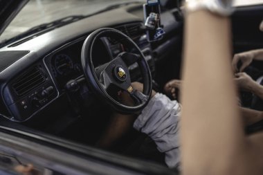 Milan, İtalya 20 Eylül 2025: Özel direksiyon, gösterge paneli ve direksiyonda elleri olan klasik klasik bir arabanın iç mekanı.