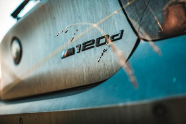 Milan, İtalya 20 Eylül 2025: toz ve yol kiri ile kaplı bm120d arka, görünür yazı ve model, metalik boya mavi gökyüzünü yansıtıyor ve seyrek güneş ışığı çimenleri