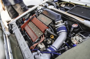 Milan, İtalya, 20 Eylül 2025: abarth yarış motoru karmaşık mekanik parçaları ortaya çıkarıyor ve yüksek performans için özel ayarlar yapıyor, arka planda teknik detayları izleyen bir kişi var.