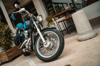 Milan, İtalya 20 Eylül 2025: Siyah vintage helikopter motosikleti şehir kaldırımına park edilmiş, mavi başlık ve krom detaylarıyla klasik tarz ve şehir macerası hissi yaratıyor.